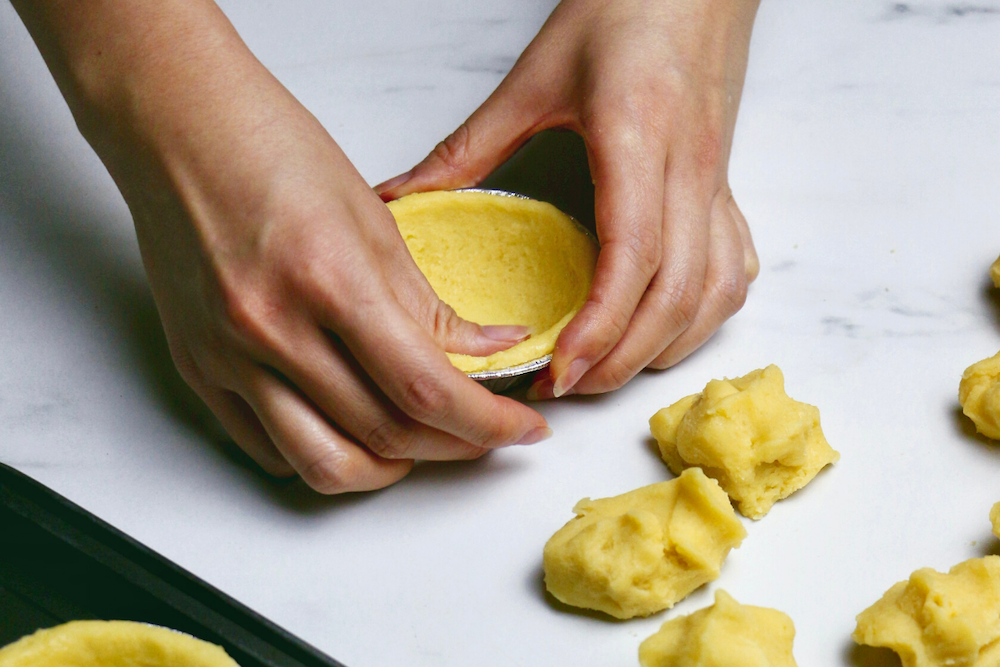 a baker carries a cart with a baking tray with raw dough into a